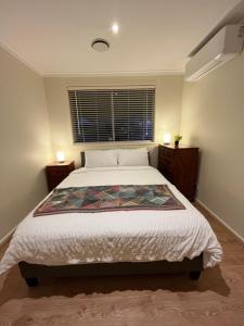 ein Schlafzimmer mit einem großen Bett und einem Fenster in der Unterkunft Cosy 3 bedroom family home near beach and shops in Frankston