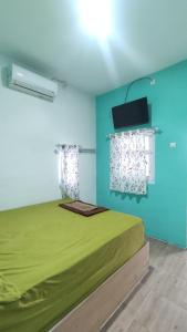 a bedroom with a bed and a tv on the wall at Rumah Teman Hostel in Semarang