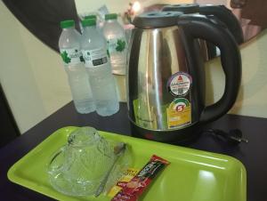 a green tray with a tea kettle and bottles of water at Anmol Hotel Thai Smile Group in Pattaya Central