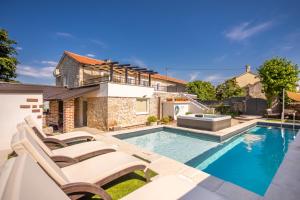 a swimming pool with chairs and a house at Villa Hrustika - heated pool, jacuzzi & sauna in Gabonjin