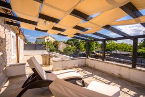 patio z białymi krzesłami i markizą na dachu w obiekcie Villa Hrustika - heated pool, jacuzzi & sauna w mieście Gabonjin