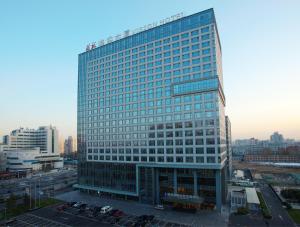 北京北京唯实酒店（唯实国际文化交流中心）的一座高大的玻璃建筑,前面有汽车停放