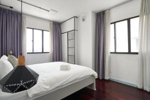 - une chambre avec un grand lit, des draps blancs et des fenêtres dans l'établissement 2BR apartment overlooking downtown, à Hô-Chi-Minh-Ville