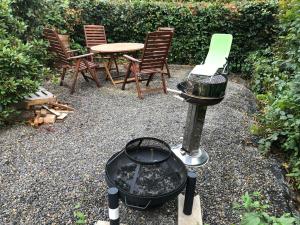 einen Grill mit Stühlen und einem Tisch im Hinterhof in der Unterkunft Ferienwohnung Grüner Weg mit Grillplatz in Tecklenburg