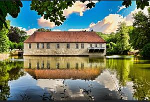 una vieja casa en el agua en un lago en Ferienwohnung Grüner Weg mit Grillplatz en Tecklenburg