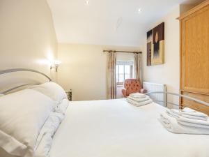 a bedroom with a white bed and a chair at The Hayloft - Uk44519 in Tetney