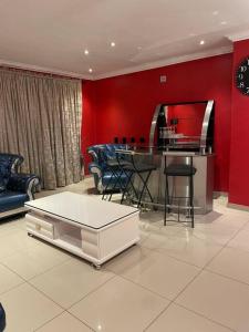 sala de estar con mesa y pared roja en Sermj Abode Nkoyoyo, en Mbabane
