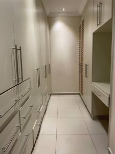 a bathroom with white walls and white tile floors at Sermj Abode Nkoyoyo in Mbabane