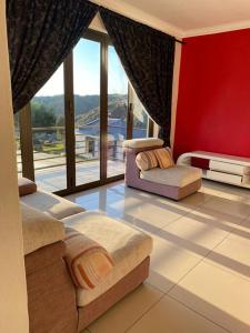 a living room with two chairs and a large window at Sermj Abode Nkoyoyo in Mbabane