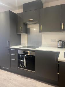 een keuken met zwarte kasten en een zwarte oven bij New modern 1 bedroom duplex apartment Hemel Hempstead High Street in Hemel Hempstead