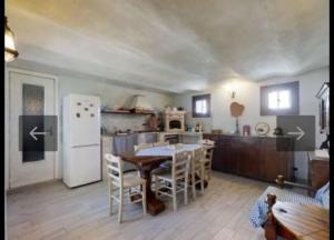 een keuken met een tafel en een witte koelkast bij The blue country house in Cavour