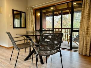 a dining room with a table and chairs and a balcony at Peaceful cottage in beautiful landscaped native bush gully in Tamahere