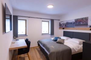 a bedroom with a bed and a desk and windows at Boutique Hotel Vila Loka in Škofja Loka