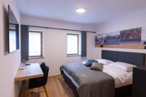 1 dormitorio con 1 cama, escritorio y ventanas en Turizem Loka - Hotel Vila Loka, en Škofja Loka