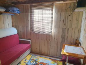a small room with a red couch and a table at Planinska Bajka pogodna za dnevne boravka i one koji se vole in Olovo