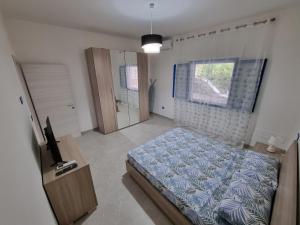 a bedroom with a bed and a television and a window at Villetta Azzurra in Torre Lapillo