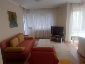 ein Wohnzimmer mit einem roten Sofa und einem TV in der Unterkunft Стая in Widin