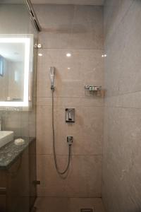 a bathroom with a shower with a sink and a mirror at Udman Hotel Gurugram in Gurgaon