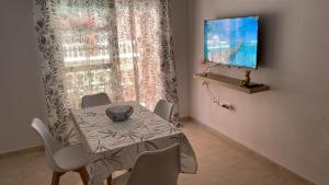 uma sala de jantar com uma mesa e cadeiras e uma televisão em Apartamento PUERTO em Mazagón