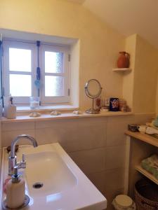 ein Bad mit einem Waschbecken und einem Fenster in der Unterkunft Hameau de Leignoua in Le Saint