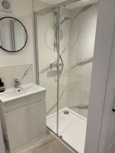 baño blanco con ducha y lavamanos en The Lodge Hideaway in Cowes, en Gurnard
