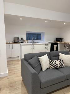 uma sala de estar com um sofá cinzento e uma cozinha em The Lodge Hideaway in Cowes em Gurnard