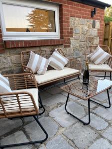 un patio con 2 sillas de mimbre y una mesa en The Lodge Hideaway in Cowes en Gurnard