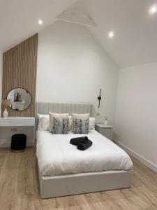 Dormitorio blanco con cama blanca y espejo en The Lodge Hideaway in Cowes en Gurnard