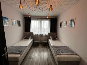 two beds in a room with a window at Apartament 70’s in Kołobrzeg