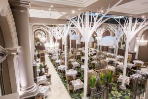 une salle à manger avec des tables blanches et des lustres dans l'établissement Grand Hôtel Des Thermes, à Saint-Malo