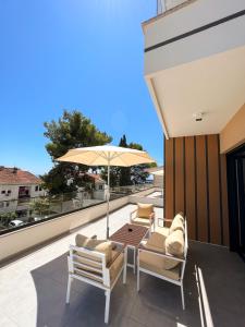 eine Terrasse mit Tisch, Stühlen und Sonnenschirm in der Unterkunft Square Residence & Pool in Ulcinj