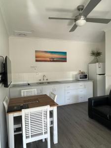 a kitchen with a table with chairs and a refrigerator at Busselton Jetty Chalets in Busselton