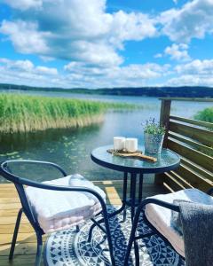 a table and chairs on a deck with a view of the water at Björkudden glamping in Fristad