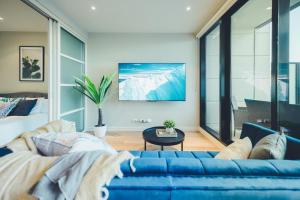 sala de estar con sofá azul y cama en Molly's Little Apartments, en Melbourne