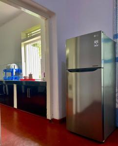 une cuisine avec un réfrigérateur en acier inoxydable dans une pièce dans l'établissement Red Araliya Villa Weligama, à Weligama
