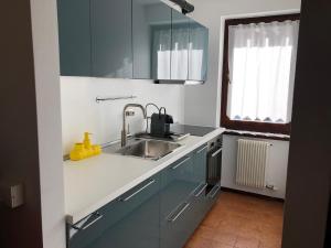 een keuken met blauwe kasten en een wastafel bij 051 Trilocale piano terra, Pinzolo in Pinzolo