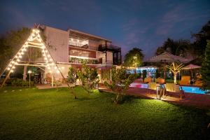 a house with lights in the yard at night at The Modeva Hotel in Kanchanaburi