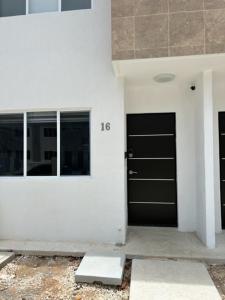 a white building with two black doors on it at Cancun 16, South 6 Person 3 Rooms 15 min Airport 20 to Beach in Cancún