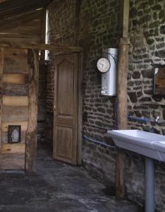 La salle de bains est pourvue d'un lavabo et d'une horloge sur un mur en briques. dans l'établissement La Billardière Camping à la Ferme, à Le Ménil-Ciboult