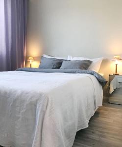 a white bed in a bedroom with two lamps at Aurora Home Kivistö 1-bedroom apartment for up to 8 near Helsinki Vantaa Airport and Helsinki city center in Vantaa