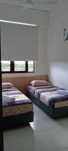 two beds sitting in a room with a window at D'yana Imperio Homestay in Alor Setar