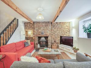 a living room with a red couch and a stone fireplace at Weavers Cottage in Barrowford
