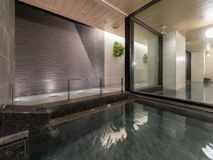 a swimming pool in a building with a large window at Nishitetsu Hotel Croom Hakata Gion Kushida Shrine in Fukuoka