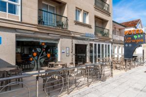 un restaurante con mesas y sillas fuera de un edificio en Hotel Los Naranjos, en A Revolta