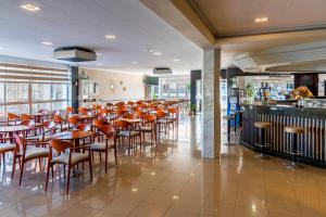 a restaurant with orange chairs and tables and a bar at Hotel Los Naranjos in Revolta