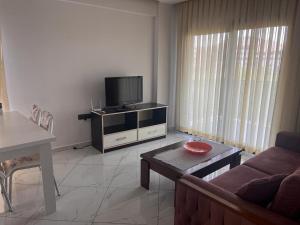 a living room with a couch and a flat screen tv at MAYA APARTMANI in Kusadası