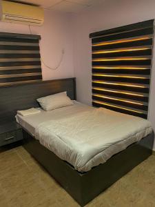 a bedroom with a large bed with a wooden headboard at Dabb Apartments in Ilorin