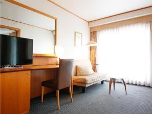 a hotel room with a desk with a television and a chair at Hotel BELLMARE ホテルベルマーレ in Maizuru