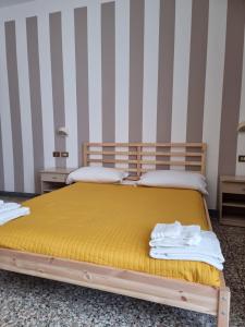 1 Schlafzimmer mit 2 Betten mit gelber Bettwäsche und gestreiften Wänden in der Unterkunft Beach Hotel Clerice in Rimini