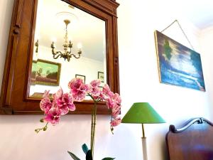 un espejo en una habitación con un jarrón de flores en CHATA OTWARTYCH OKIENNIC Pokoje Gościnne, en Supraśl